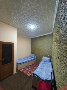 a small room with two beds and a wall at Muslima Guest House in Muruntau