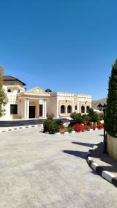 a large white building with a courtyard with flowers at منتجع وفيلا تل الرمان in Ar Rummān