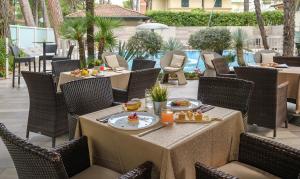 a restaurant with tables and chairs with food on them at Hotel Alexander in Milano Marittima