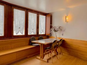 Un comedor con mesa y sillas y ventanas. en Charlotte Lodge 28, en Breuil-Cervinia