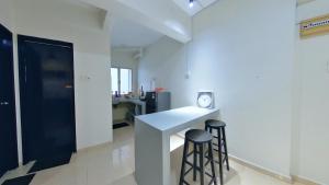 a kitchen with two stools and a counter with a clock at 2-5pax Sunshine BeachFront, Wifi, 50"TV, FREE PARKING & POOL in Port Dickson