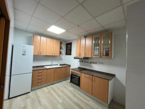 a kitchen with wooden cabinets and a white refrigerator at La Muralla in Montblanc
