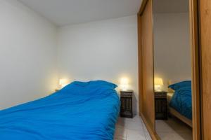 Un dormitorio con una cama azul y un espejo. en Gilles 124, en Ostende