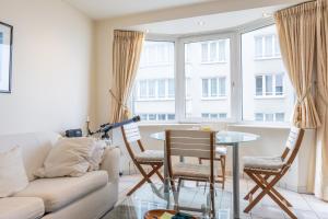 Una sala de estar con un sofá, una mesa y sillas. en Gilles 124, en Ostende