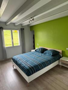 a bedroom with a bed with a green wall at Charmante maison basque entre ville et campagne in Arcangues
