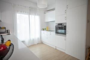 a white kitchen with white cabinets and a window at Vivid Stays Chalkokondili in Nicosia