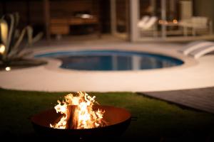 a fire pit in front of a swimming pool at VILLA Seamu 九十九里 家族と愛犬で楽しむサウナとプール ガラス貼りBBQルーム付き高級ガーデンヴィラ in Kujukuri