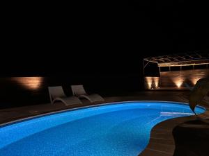 a swimming pool at night with two chairs and lights at VILLA Seamu 九十九里 家族と愛犬で楽しむサウナとプール ガラス貼りBBQルーム付き高級ガーデンヴィラ in Kujukuri