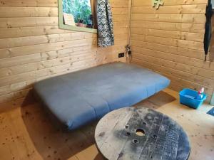a blue bed in a wooden room with a table at La cachouette in Bressuire