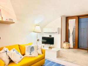 a living room with a yellow couch and a tv at Acqua Marina - UN LETTO IDEALE in Gaeta