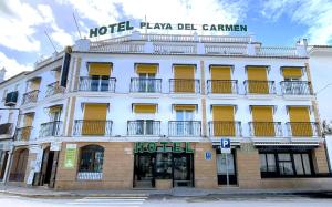 a large white building with yellow shutters on it at Hotel Playa del Carmen in Barbate