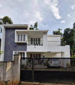 a white house with a black fence at Parthees Homestay in Meppādi