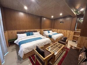 a bedroom with two beds and a table in it at Hotel Ganpati in Lohaghāt