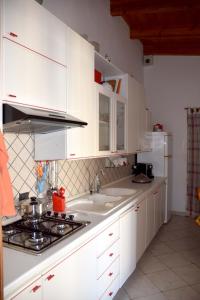 a kitchen with white cabinets and a sink and a stove at Sara Relax Home in Mazara del Vallo