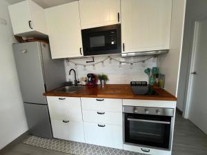 a kitchen with white cabinets and a sink and a microwave at Menorca Palm Villa in Cala en Blanes