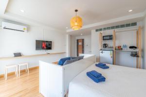 a bedroom with a white bed and a kitchen at De Blue Door, Hatyai in Hat Yai