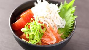 a black bowl filled with vegetables and other foods at Dormy Inn Mishima in Mishima