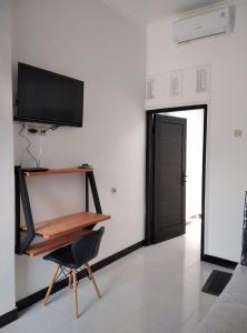 Una habitación con un escritorio y un televisor en la pared. en Pondok Barokah 1, en Tanjungkarang
