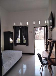 Un dormitorio con una cama, un televisor y una silla. en Pondok Barokah 1, en Tanjungkarang