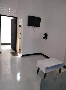 Habitación blanca con mesa y TV en la pared. en Pondok Barokah 1, en Tanjungkarang
