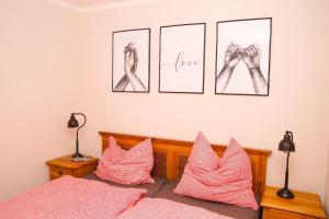 a bedroom with a bed with pink pillows and drawings on the wall at Holzhaus Hubertus mit Sauna und Kamin in Meschede