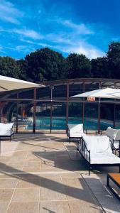 a patio with tables and umbrellas in front of a building at Gite chez mary au domaine du château de ragny in Savigny-en-Terre-Plaine