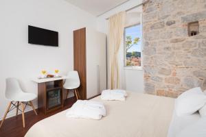 a bedroom with two beds and a stone wall at Rooms Supreme Spalato in Split