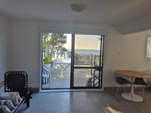 a living room with a sliding glass door with a view of the ocean at Raumati South Beach Studio in Paraparaumu