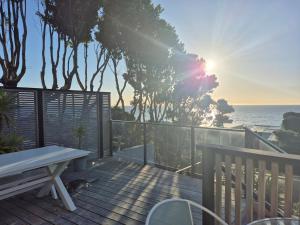 Un gato tumbado en una terraza de madera con vistas al océano. en Raumati South Beach Studio, en Paraparaumu