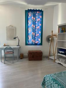 a room with a window with a blue curtain and a desk at Le petit velo rouge in Arles