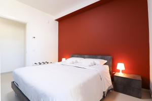 una camera da letto con un letto bianco e una parete rossa di Dimora del Corso - L'Aquila a L'Aquila
