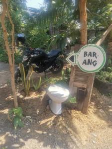 una motocicleta aparcada junto a un inodoro en un jardín en Bar Ang Guesthouse, en Battambang
