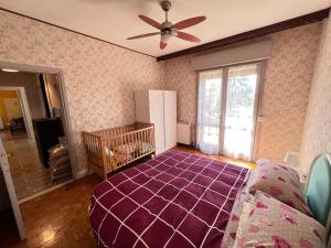 une chambre avec un berceau et un ventilateur de plafond dans l'établissement Villa Egles - Villa con giardino a Lignano Sabbiadoro, à Lignano Sabbiadoro