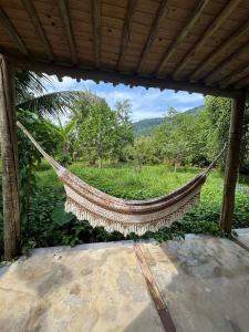 a hammock hanging from a building with a view of a field at Casa natureza Paraty I in Paraty