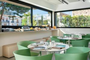 a restaurant with two tables and green chairs at Ollen apartments in Catania