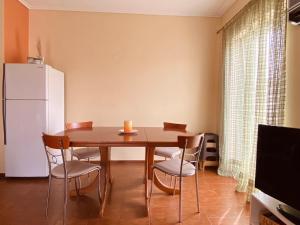 a dining room table with chairs and a white refrigerator at Oasis Paralio Astros in Paralio Astros