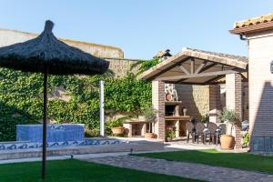 un patio con ombrellone, tavoli e sedie di La Casa de las Flores Casa Rural a Pulgar