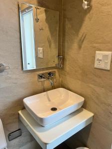 ein weißes Waschbecken in einem Badezimmer mit einem Spiegel in der Unterkunft Le Boho Shimla in Shimla