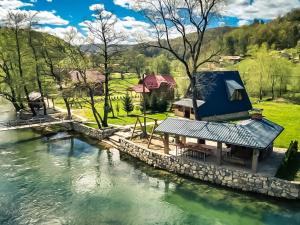 a house with a blue roof next to a river at Vikendica Mia in Šipovo