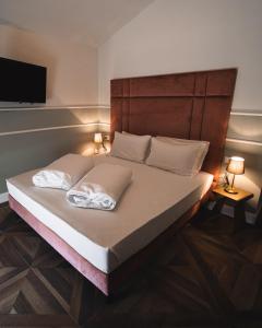 a bed with two white pillows on it with a television at Locanda Gaudemus Boutique Hotel in Sistiana