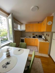a kitchen with yellow cabinets and a table and chairs at Apartment RENA - private parking in Sarajevo
