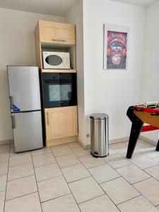 a kitchen with a refrigerator and a microwave at La Terrasse vue étangs, Babyfoot, jeux de société by BookingFuté in Socourt +13 photos