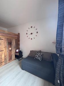a living room with a couch and a clock on the wall at Valley View Studio in Saint Vincent