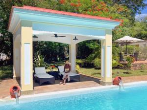 a woman sitting in a gazebo next to a swimming pool at Hilda's Homestay in Diani Beach
