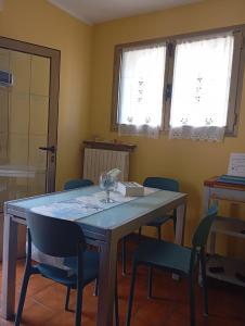 a dining room with a table and chairs and two windows at La casa di nonna Mary in Diano Castello