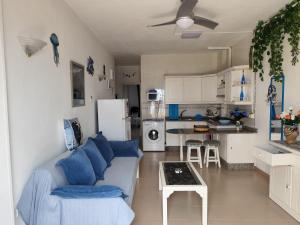 a living room with a blue couch and a kitchen at Arenas Blancas 203 in La Restinga