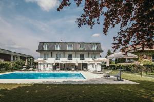 a large house with a swimming pool in front of it at Aquavista Residence - Lake & Poolside Vacation Homes in Castelletto sopra Ticino
