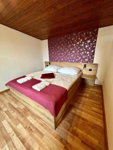 a bedroom with a large bed with a purple wall at Drevený Raj Apartmán in Hrabušice +15 photos