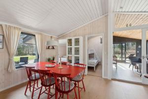 a dining room with a red table and chairs at Cozy Summer House In North Jutland in Jerup