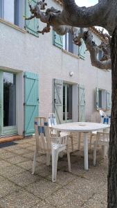 a table and two chairs sitting next to a tree at Villa du Moulin vers la Mer in Fleury